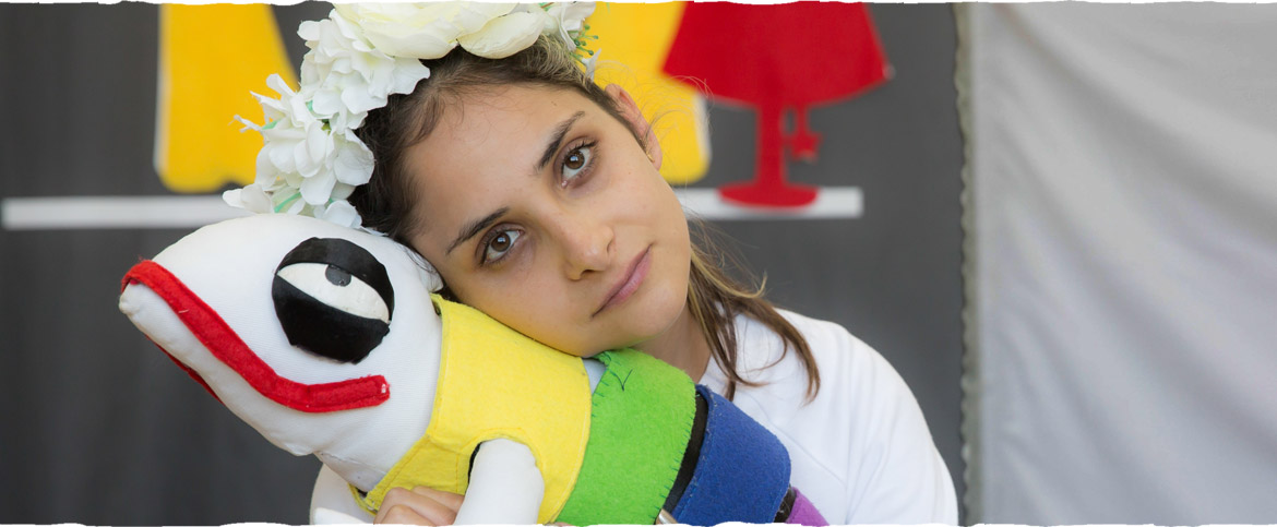 אילוסטרציה להצגה "אספן הצבעים" - ילדה עם זר פרחים על הראש, מחבקת איגואנה צבעונית