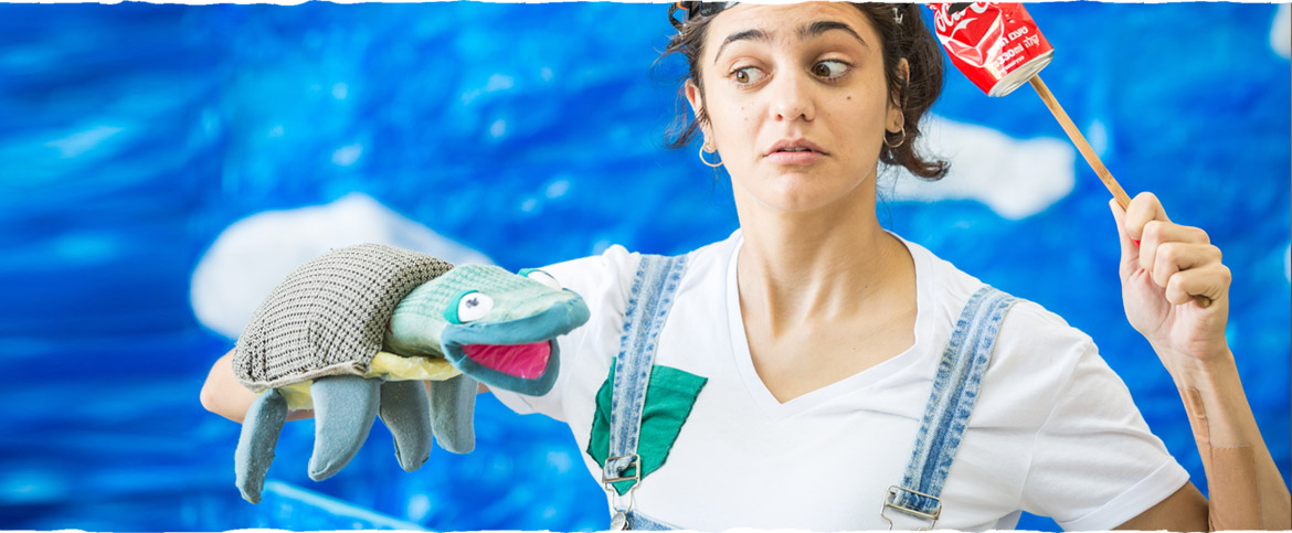 צילום מתוך ההצגה "אלה חוקרת הים" - הדמות הראשית אוחזת בפחית שתייה ומנהלת שיחה עם צב ים